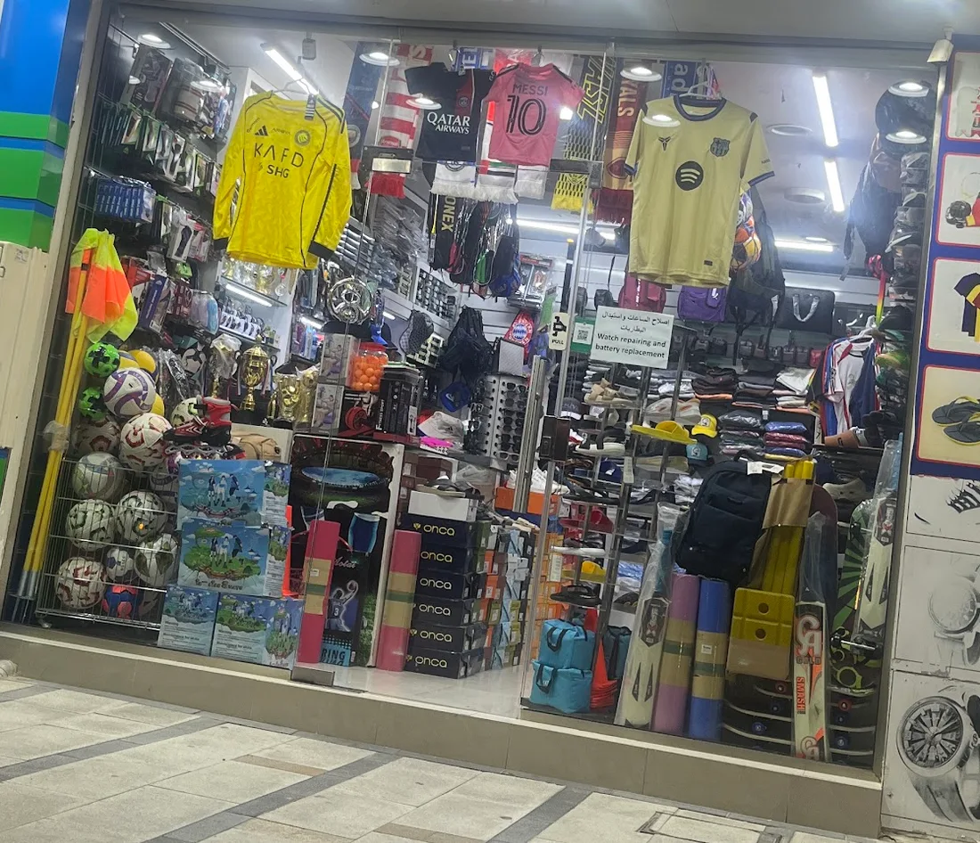 The shop window at night, lit up with jerseys and balls on display